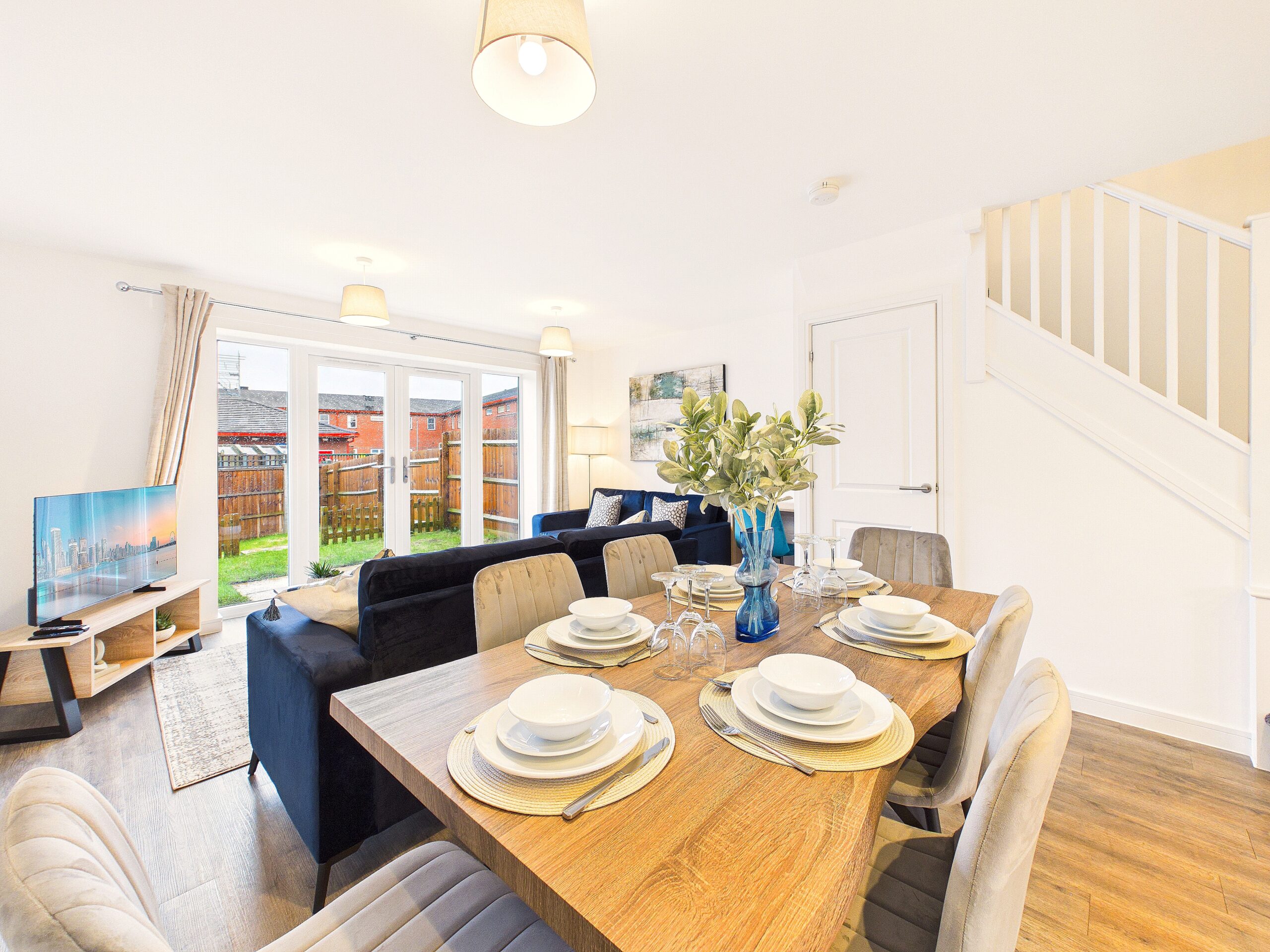 Nightingale - Living Area (4) Bright dining and living area with large table and blue sofas.